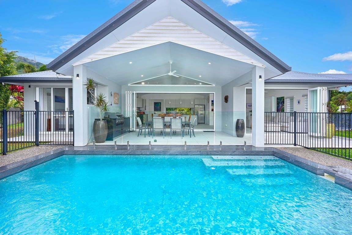 A modern house with a swimming pool, a covered patio, and a view of the surrounding landscape.