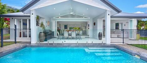 A modern house with a swimming pool, a covered patio, and a view of the surrounding landscape.