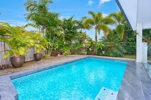 A swimming pool surrounded by tropical plants and a wooden fence. - Seaside Haven | 4 Bedroom Holiday Home with Private Pool (Palm Cove)