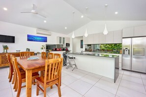 A modern kitchen with a central island, white cabinetry, and stainless steel appliances. - Seaside Haven | 4 Bedroom Holiday Home with Private Pool (Palm Cove)