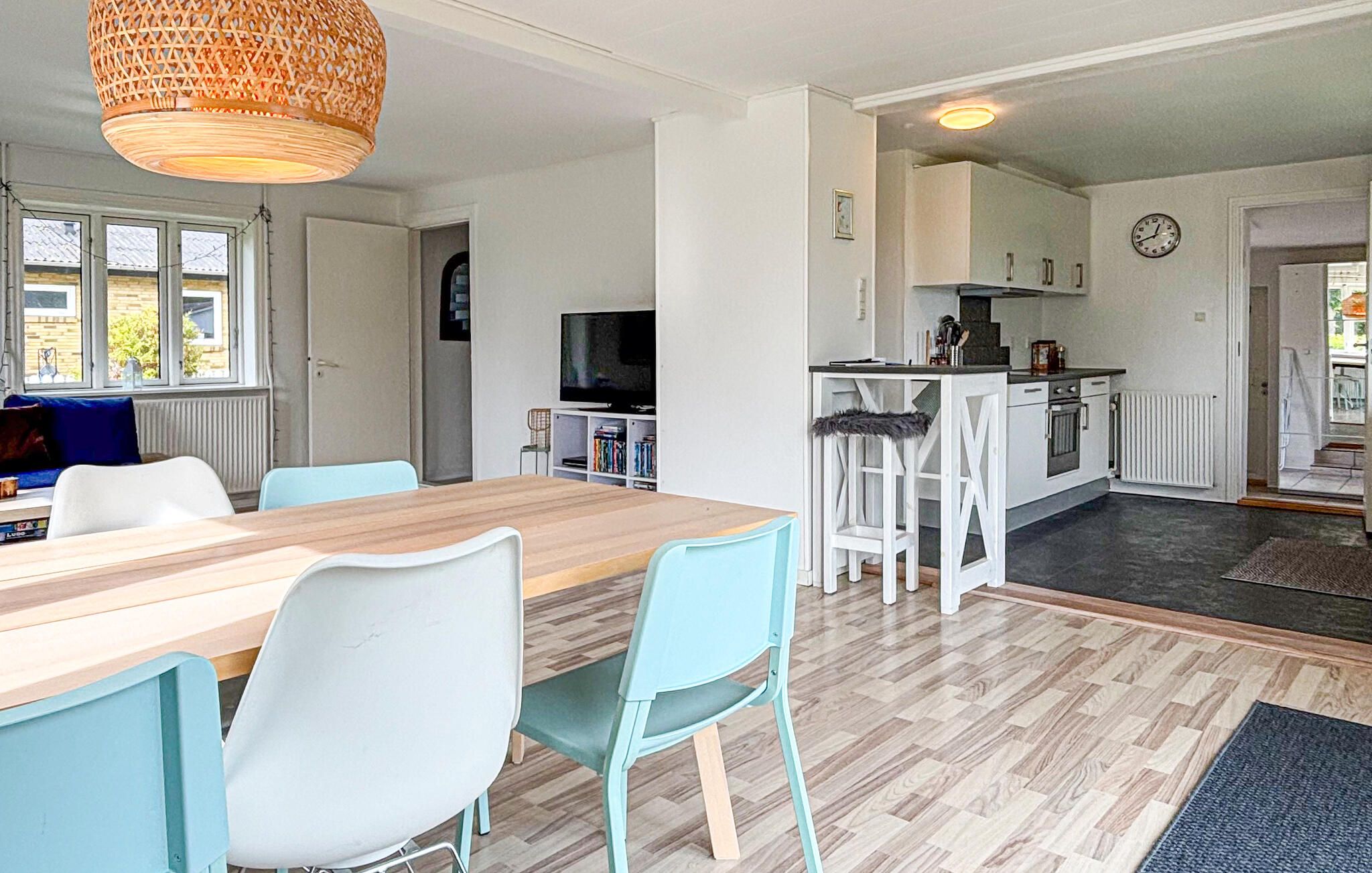 Une cuisine moderne avec des meubles blancs, une table à manger en bois et des chaises bleu clair.