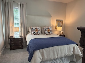 Une chambre à coucher comprenant un lit, une commode, une table de chevet, une lampe et un miroir.