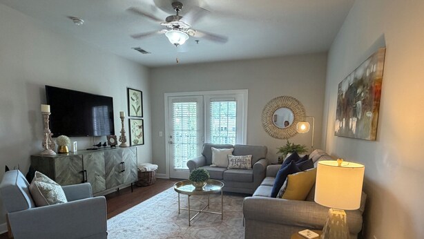 A living room with a sofa, armchairs, a coffee table, a TV, and a ceiling fan. - "Rebel Depot" - By OVR (Oxford)