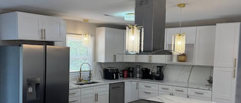 A modern kitchen with a central island, stainless steel appliances, and pendant lighting.