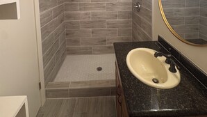 Ein Badezimmer mit Dusche, Waschbecken und Spiegel.