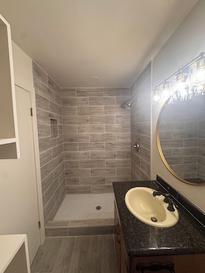 Un baño con ducha, lavabo y espejo.