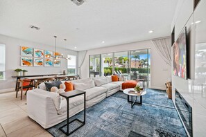 A modern living room with a sectional sofa, a coffee table, and a dining area with a table and chairs. - Chic and Stylish 4 Bedroom Haven in Reunion Resort (Orlando)