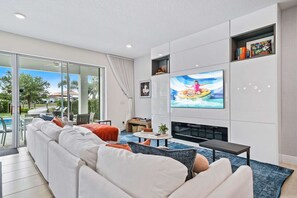 A modern living room with a flat-screen TV, a fireplace, and a large sofa. - Chic and Stylish 4 Bedroom Haven in Reunion Resort (Orlando)