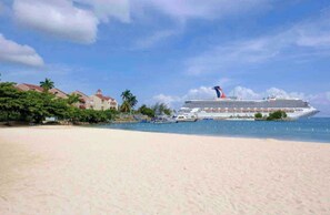 A cruise ship docked at a beach with a clear sky. - Searenity Beachfront View Hotel Apartment #29 Ocho Rios (Ocho Rios)