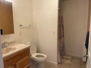 Un baño con inodoro, lavamanos y zona de ducha.