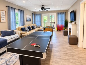 Una sala de estar con mesa de ping pong, sofá y mesa de fútbol.