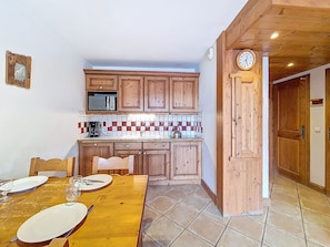 Eine kleine Küche mit Holzschränken, einer Mikrowelle und einer gefliesten Spritzschutzwand.