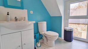 A bathroom with a white sink, a toilet, and a trash bin.