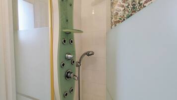 Eine Dusche mit einer grünen Vertuschung, einer Handbrause und einem am Wand montierten Wasserhahn.