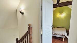 A room with a wooden staircase, a bed with a green wall, and a white door. - Country house, pets allowed - 7 guests (Hambers)