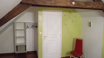 Ein Zimmer mit einer weißen Tür, einem roten Sessel, einer weißen Regaleinheit und einem Holzbalken an der Decke.