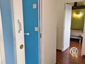 A room with a blue door, a bed with a green wall, and a logo on the floor.