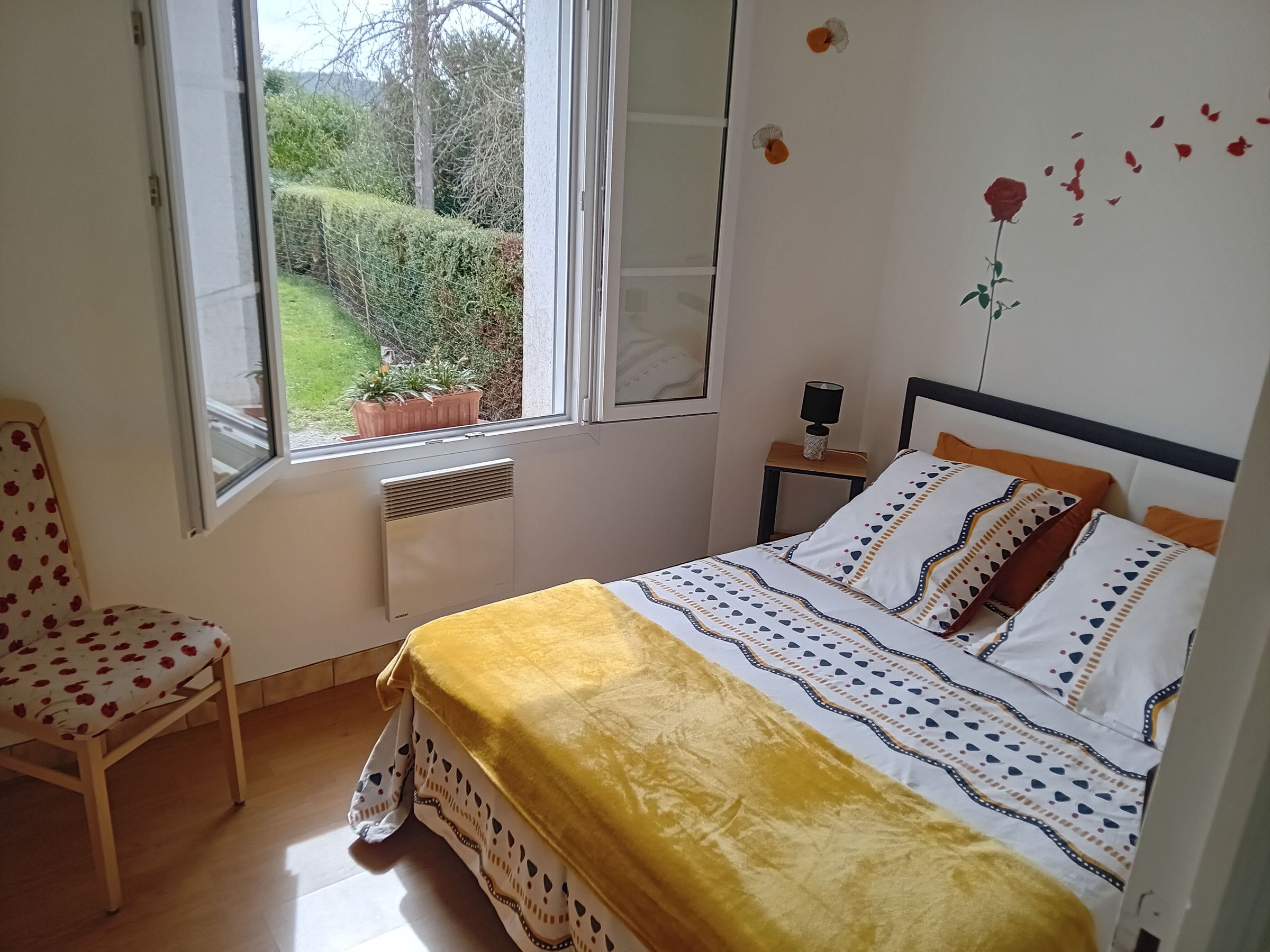 Ein Schlafzimmer mit einem Bett, einem Sessel, einem Fenster und einem kleinen Tisch.