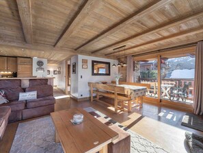 Un espacio habitable amplio con techo de madera, un sofá, una mesa de centro y una mesa de comedor con sillas.