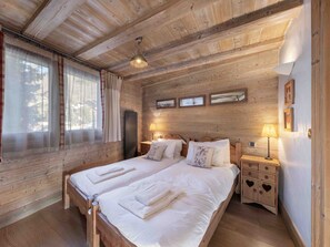 A wooden cabin bedroom with two beds, a nightstand, a dresser, and a ceiling fan. - Spacious apartment with South terrace - 6 guests (Méribel)