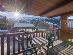 A wooden deck with a table and chairs, overlooking a snowy mountain landscape. - Spacious apartment with South terrace - 6 guests (Méribel)