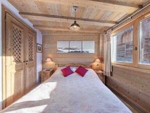 A wooden room with a bed, two bedside tables, a hanging light fixture, and a window with curtains. - Spacious apartment with South terrace - 6 guests (Méribel)