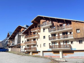 A multi-story hotel with wooden balconies and a mountain backdrop. - Apartment with wifi, mountain view - 7 guests (Valfréjus)