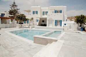 A white building with a pool, outdoor seating, and a pergola. - Gelos House (Mykonos)