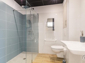 Un baño moderno con ducha de vidrio, inodoro blanco y lavamanos con espejo.