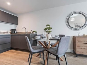 A modern kitchen with a dining table and chairs, a potted plant, and a mirror on the wall. - Modern 2BR City Centre Stay Near Hospital (Liverpool)