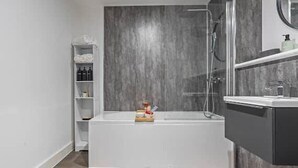 Ein modernes Badezimmer mit einer Badewanne, Dusche und einem Waschtisch mit Spiegel.
