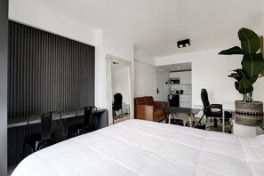 Et moderne hotelværelse med en stor seng, et skrivebord, en stol og et spiseområde.