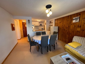 Espai habitable reduït amb zona de menjador, petita cuina i sofà.
