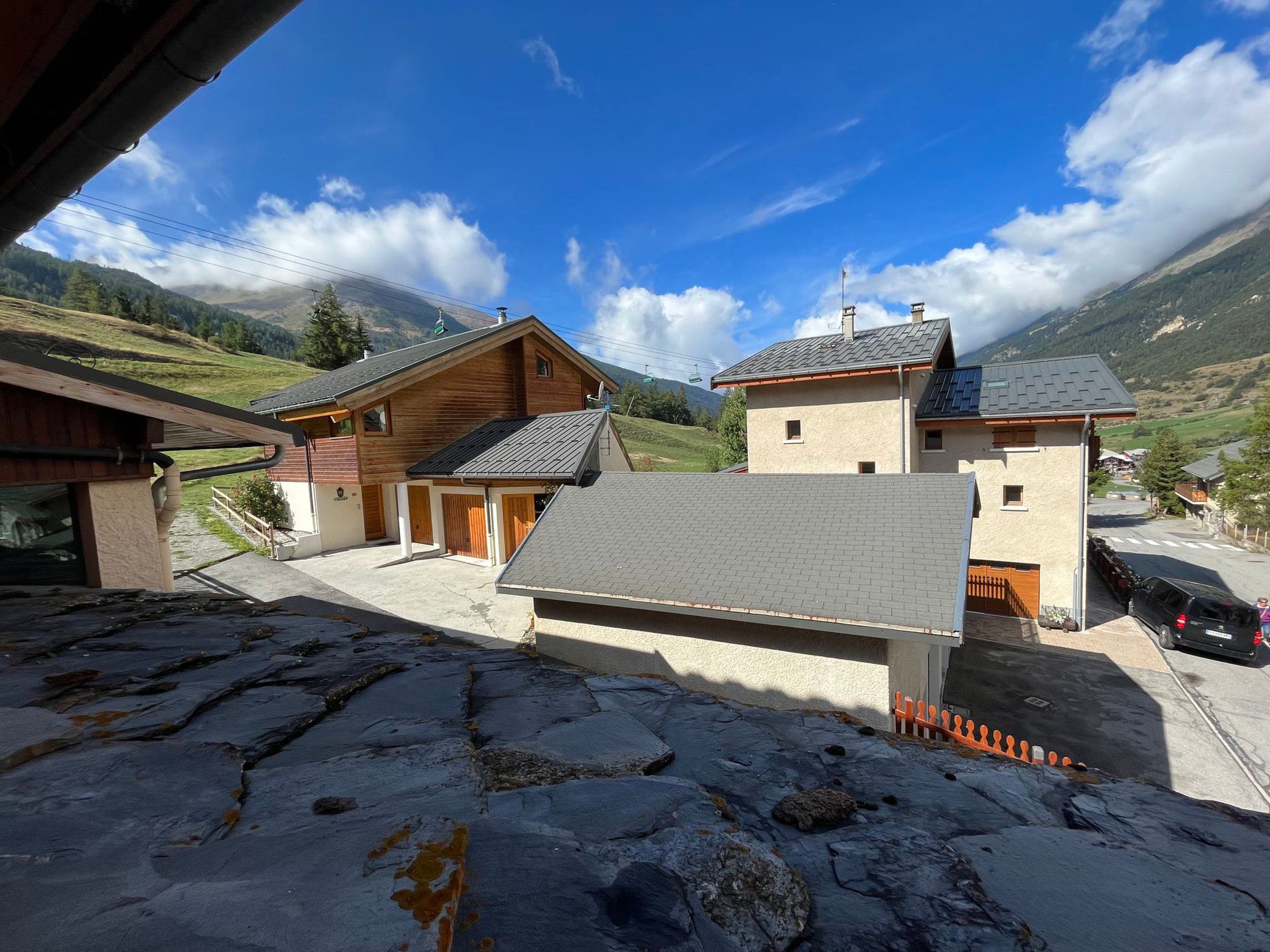 Un village de montagne isolé, avec ses maisons traditionnelles en bois, une route pavée et un ciel bleu azur.