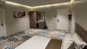 Hotellihuone, jossa on suuri sänky, yöpöytä, peili ja kuviollinen lattia.