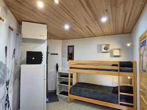 A room with a bunk bed, a white cabinet, a desk, and a wall-mounted shelf. - Studio for 4, South facing (Valloire)