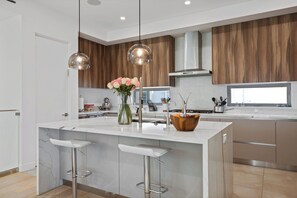 Een moderne keuken met een centraal eiland, hanglampen en houten kastjes.