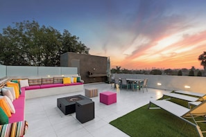 An outdoor patio with a seating area, a fire pit, and a dining setup.