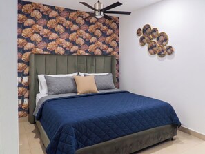 Una camera da letto con un letto, una ventola a soffitto, una parete decorata con un motivo floreale e un elemento decorativo a parete.