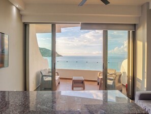 Una camera moderna con un'ampia porta scorrevole in vetro che dà su un balcone con vista sul mare.
