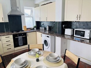 Cozinha moderna com fogão, micro-ondas e máquina de lavar roupa.