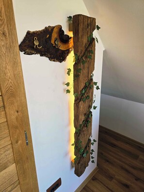 Ein an der Wand befestigtes Holzteil mit rustikalem Design, das eine geschnitzte Fläche und Efeu zeigt.