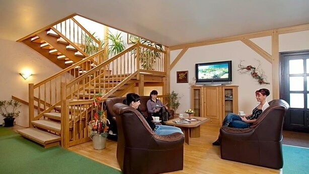 Una sala de estar con escalera de madera, sofás de cuero, televisor y chimenea.