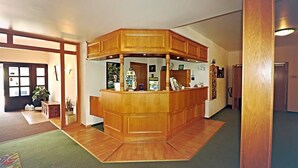 Un área de recepción con mostrador de madera, una mesa de recepción y un teléfono instalado en la pared.