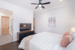 Una camera da letto con un letto, una televisione su un mobile, una ventola a soffitto e una porta.