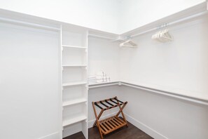 Ein begehbarer Kleiderschrank mit weißen Wänden, Holzböden und einer Kleiderstange.