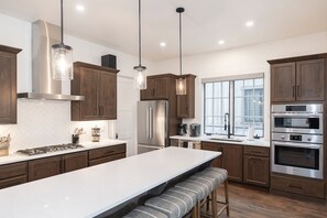 Eine moderne Küche mit Edelstahlgeräten, Holzschränken und Pendelleuchten.