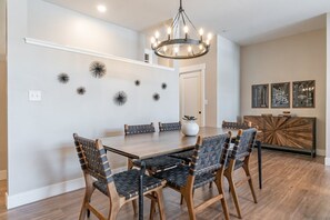 A dining area with a wooden table and chairs, a chandelier, and wall decorations. - Hideaway Haven | Tucked Away | Near Downtown (Winter Park)