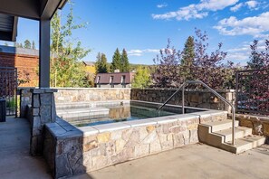 A stone hot tub with steps leading up to it, surrounded by a stone wall and a metal railing. - Hideaway Haven | Tucked Away | Near Downtown (Winter Park)