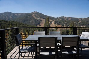 Eine Terrasse mit Tisch und Stühlen mit Blick auf eine gebirgige Landschaft.